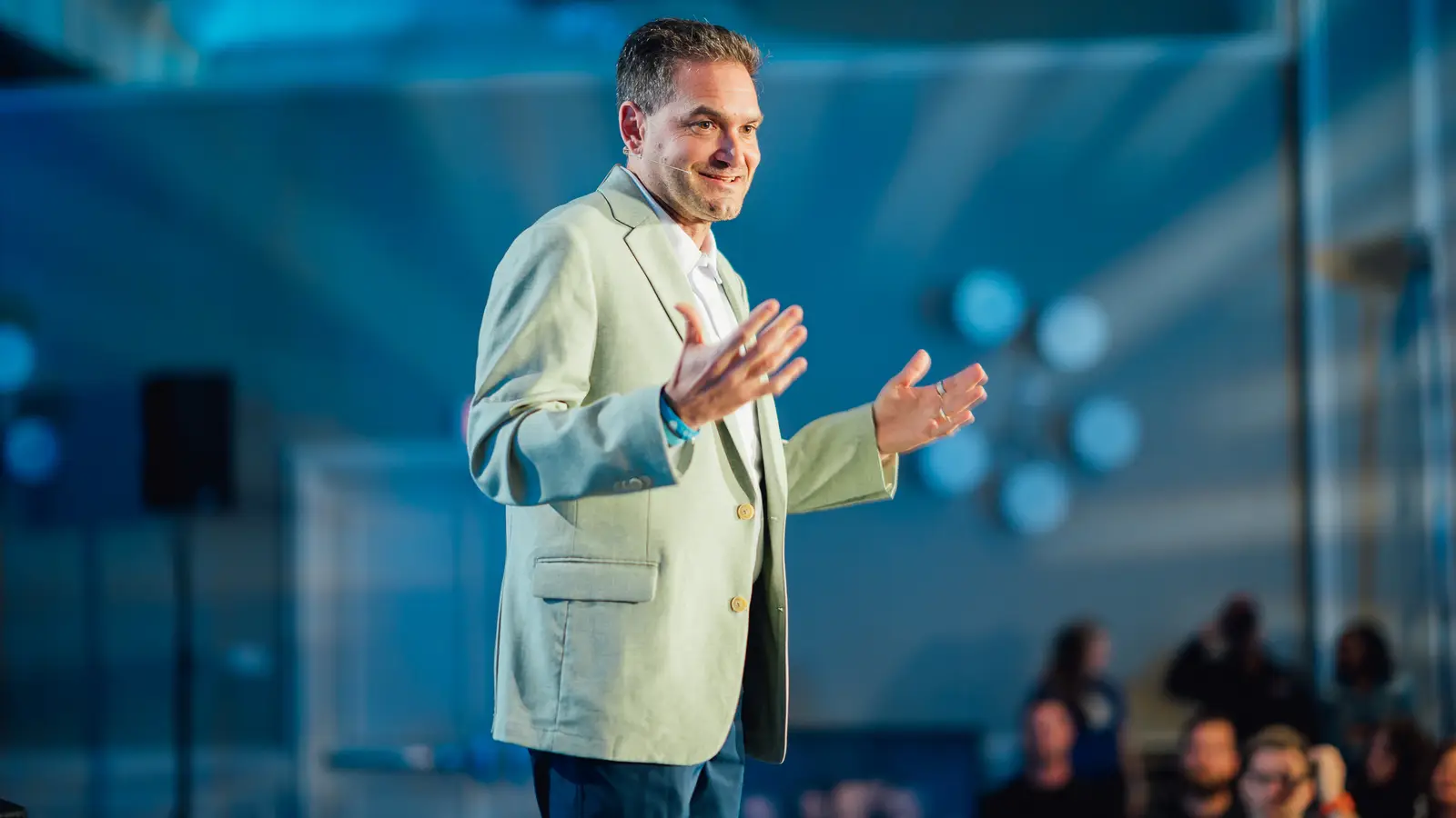Brad Holcman presenting on stage to a seated audience at a live event.
